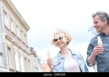 Smiling middle-aged couple holding ice cream cones sur sunny day Banque D'Images