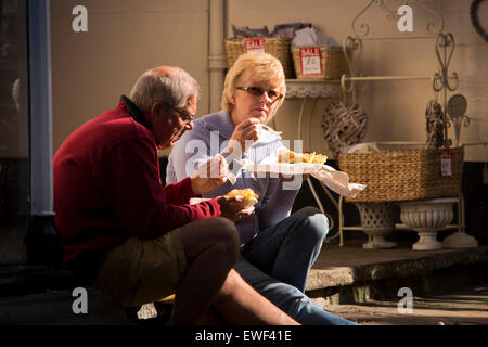 Royaume-uni, Angleterre, Shropshire, Bridgnorth, Castle Terrace, couple assis sur les marches de manger du poisson et frites Banque D'Images