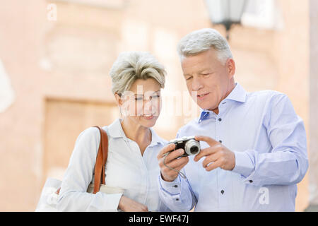 Smiling couple visualisation des photos sur l'extérieur de l'appareil photo numérique Banque D'Images