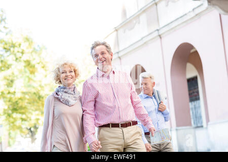 Happy middle-aged couple with map walking in city Banque D'Images