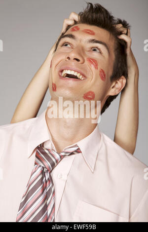 Young caucasian businessman with lipstick kiss marque sur sa joue Banque D'Images