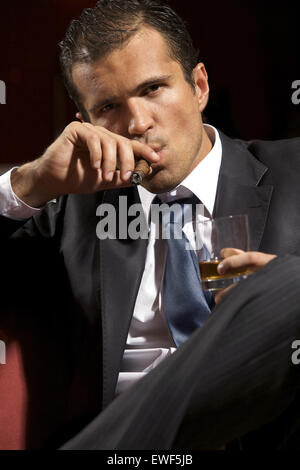 Portrait de jeune homme fumeur de cigare et holding wineglass Banque D'Images