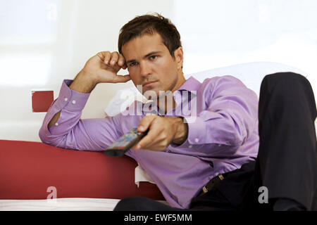 Jeune homme sur le lit avec la commande à distance Banque D'Images