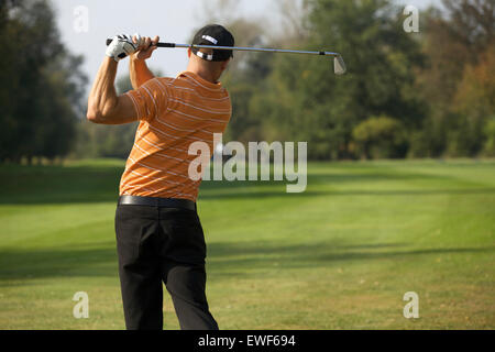 Jeune homme swinging golf club, vue arrière Banque D'Images