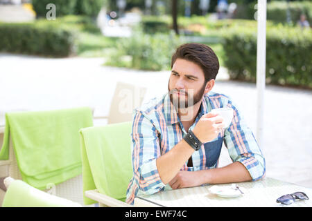 Thoughtful man holding Coffee cup at sidewalk cafe Banque D'Images