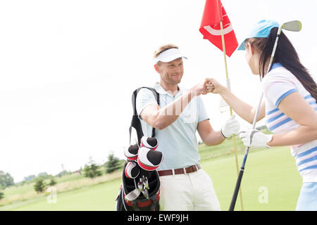 Les amis masculins et féminins de haut donnant cinq parcours de golf à Banque D'Images