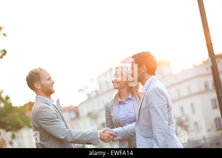 Happy businessmen shaking hands in ville contre un ciel clair Banque D'Images