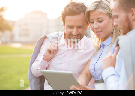 Businesspeople using digital tablet at park sur sunny day Banque D'Images