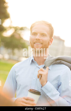 Happy businessman holding disposable cup à l'extérieur Banque D'Images