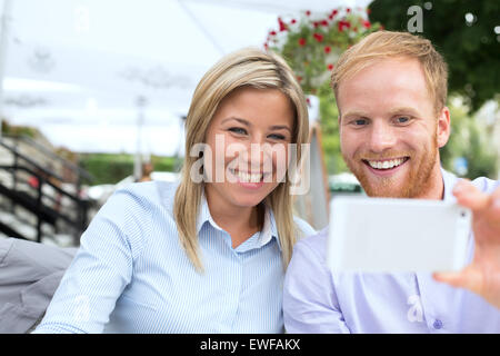 Happy business couple at outdoor restaurant selfies Banque D'Images