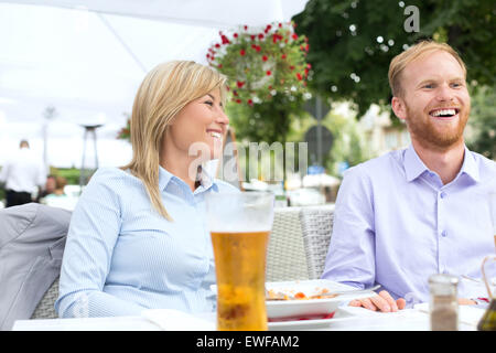 Happy businessman and businesswoman sitting at outdoor restaurant Banque D'Images