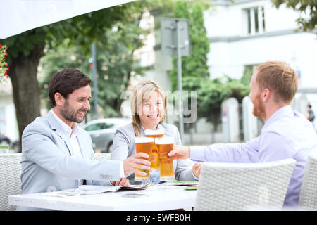Happy woman toasting beer glasses at outdoor restaurant Banque D'Images