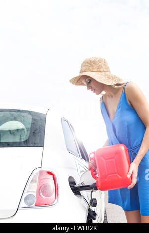 Woman refueling car contre ciel clair aux beaux jours Banque D'Images