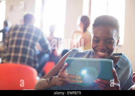 Smiling casual businesswoman using digital tablet in office Banque D'Images