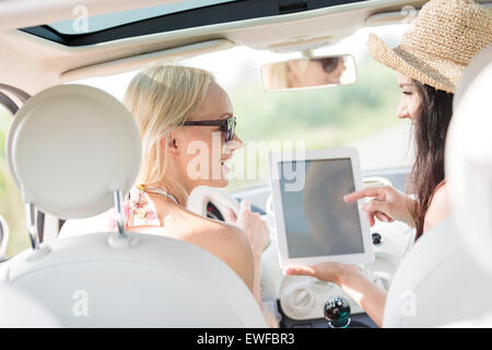 Vue arrière du happy women using digital tablet in car Banque D'Images