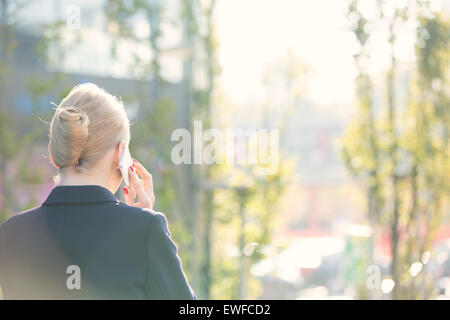 Vue arrière de businesswoman using cell phone on sunny day Banque D'Images