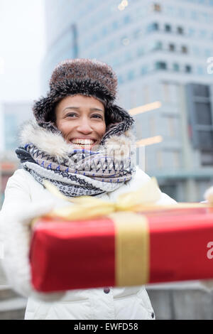 Happy woman holding gift durant l'hiver en ville Banque D'Images