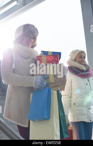 Smiling women avec des cadeaux et des sacs par fenêtre pendant l'hiver Banque D'Images