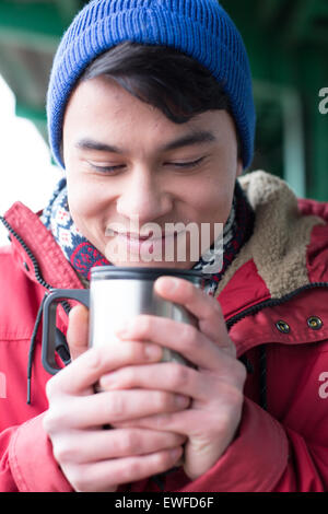 Smiling man looking at café en verre isolé conteneur lors de l'hiver Banque D'Images