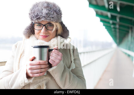 Portrait of smiling woman in vêtements chauds holding de boisson fraîche isolé Banque D'Images