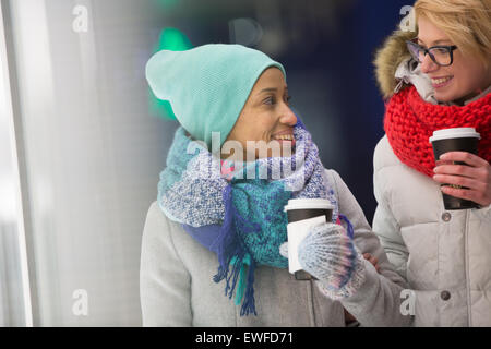 Heureux les femmes regardaient tout en maintenant des gobelets jetables Banque D'Images