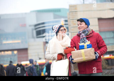 Couple heureux avec des cadeaux et des sacs à marcher en ville en hiver Banque D'Images