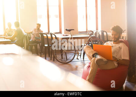 Businessman working at laptop en chaise de sac d'haricot Banque D'Images