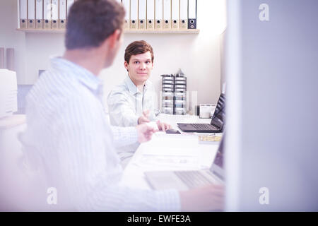 Architects discussing paperwork at desk in office Banque D'Images