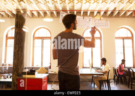 Businessman hanging revue diagrammes de l'office de tourisme Banque D'Images