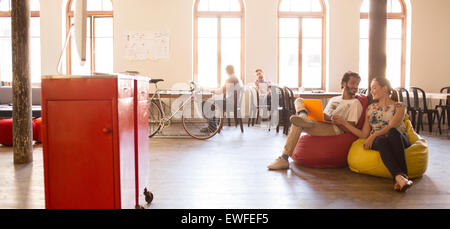 Business people working at laptop sur chaises de sac d'haricot dans open office Banque D'Images