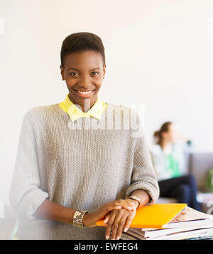 Portrait confident businesswoman with laptop et magazines in office Banque D'Images
