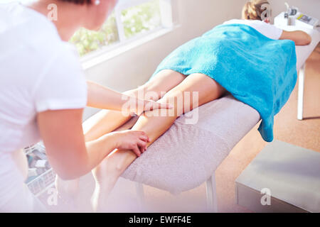 Masseuse massaging woman's leg Banque D'Images