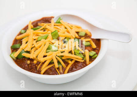 Blanc un bol de chili avec de la viande et les haricots verts et les piments poblano surmontée de fromage cheddar, râpé Banque D'Images