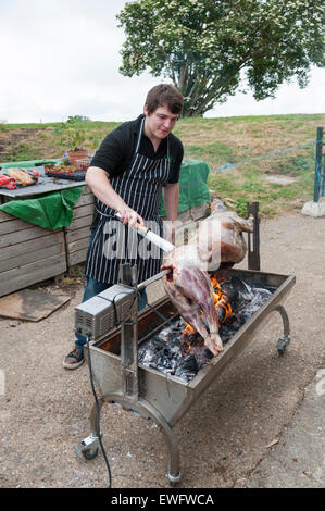 Un chef cuisiner tout un agneau sur un feu de charbon à la broche. Banque D'Images