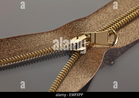 La photographie de studio golden brown zipper ouvert sur une moitié d'une surface gris Banque D'Images