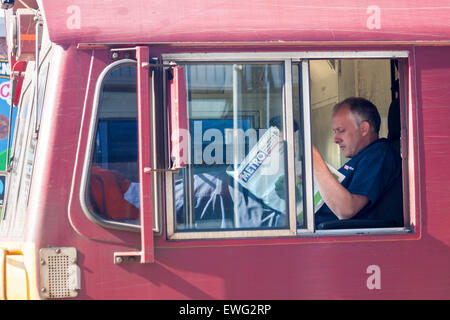 Un conducteur de train de marchandises en taxi lisant le journal du métro tandis qu'un train s'est arrêté à la gare centrale de Southampton, dans le Hampshire, au Royaume-Uni, en juin Banque D'Images