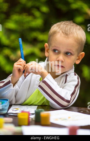 Petit garçon avec un crayon de la pensée pendant le dessin. Banque D'Images
