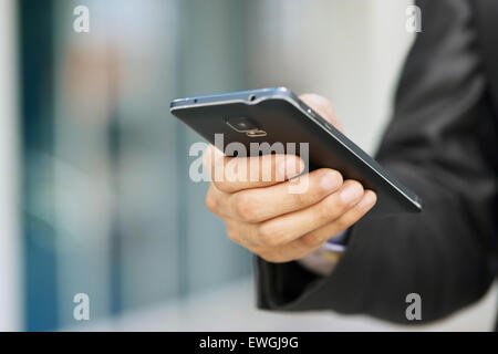 Gros plan du businessman typing note sur téléphone mobile. L'homme écrit sur son smartphone à l'aide d'une seule main avec l'immeuble de bureaux à l'arrière Banque D'Images