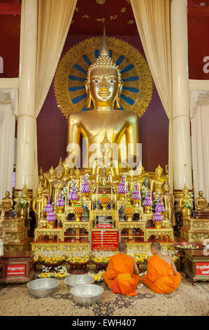 Jeunes moines en prière devant le Phra Chao Thong Astuce Buddha, Wat Phra Singh, Chiang Mai Banque D'Images