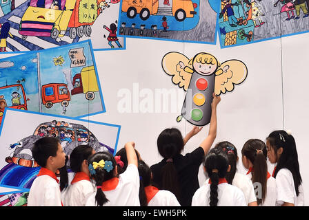 Beijing, Chine. 26 Juin, 2015. Les étudiants et vous coller les dessins animés sur un mur lors d'une cérémonie de lancement de 'Road Angel' concours de peinture pour enfants à Beijing, capitale de Chine, le 26 juin 2015. Le concours, avec la participation des enfants de 4 à 14 ans, vise à les sensibiliser à la sécurité routière. © Liangkuai Jin/Xinhua/Alamy Live News Banque D'Images