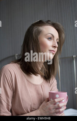 Beau young woman having coffee in bed looking away Banque D'Images