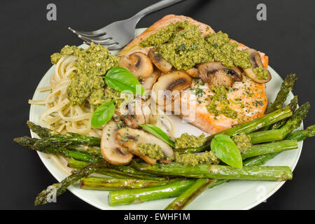 Délicieux saumon grillé avec sauce crémeuse au pesto, asperges et linguine sur le côté Banque D'Images