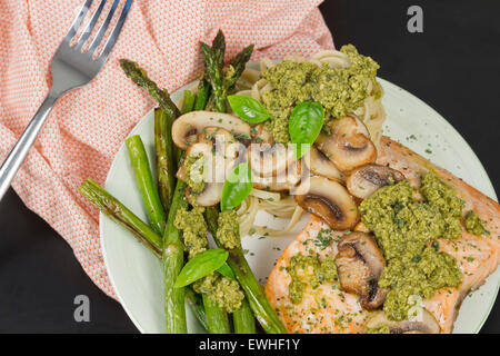 Délicieux saumon grillé avec sauce crémeuse au pesto, asperges et linguine sur le côté Banque D'Images