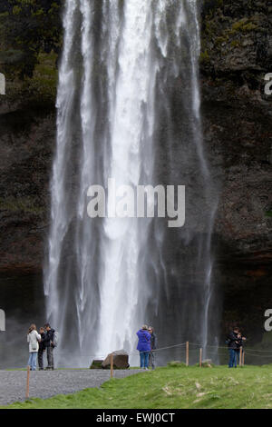 Des touristes posent pour des photos en face de la cascade de Seljalandsfoss Islande Banque D'Images