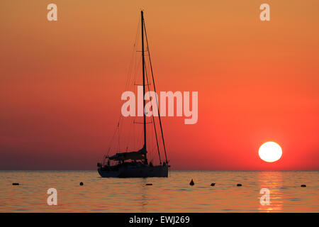 Coucher de soleil sur un yacht pour l'ancre à la baie de Ghajn Tuffieha À Malte Banque D'Images