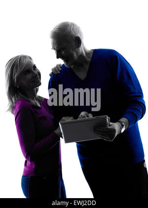 Un senior caucasian couple looking at digital tablet computer ossature en silhouette studio isolé sur fond blanc Banque D'Images