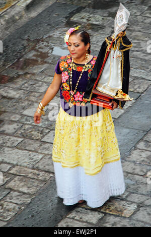 Femme mexicaine en costume traditionnel portant une statue de la Vierge Marie dans une procession Banque D'Images