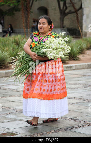 Femme mexicaine en costume traditionnel portant un grand bouquet de fleurs Banque D'Images