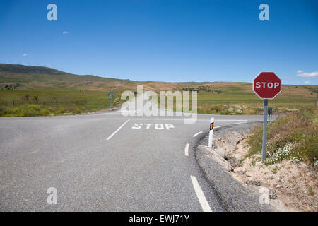 Carrefour avec symbole d'arrêt peint sur l'asphalte et rouge signal hexagonale poteau de métal en milieu rural route près de Madrid Espagne Europe Banque D'Images
