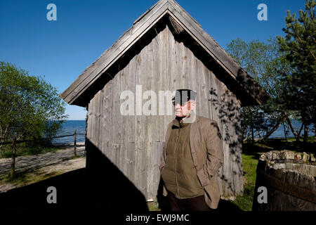 Un ancien pêcheur letton se place en avant d'une authentique maison de pêcheurs à Ragakapa Open Air Museum qui dépeint la vie quotidienne des pêcheurs au début du 20e siècle situé au pied de la dune "Ragakapa" près de Jurmala Lettonie une ville balnéaire sur le golfe de Riga à la côte de la mer Baltique, République de Lettonie Banque D'Images